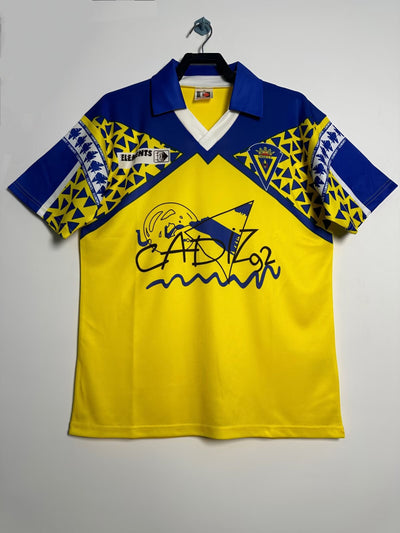 Camiseta Retro Cádiz CF 1992 amarilla y azul con diseño geométrico y gráficos "Cádiz 92".